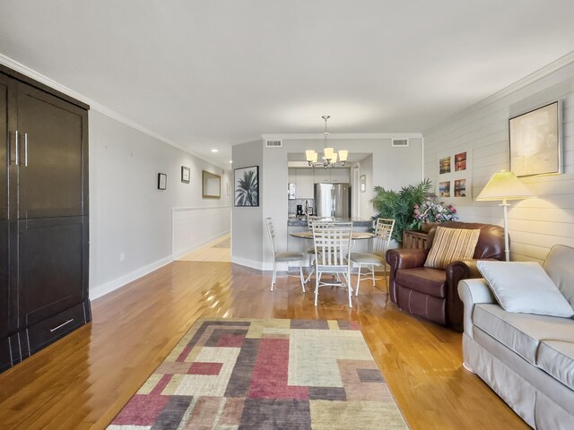 dining space featuring ornamental molding, an inviting chandelier, and wood-type flooring