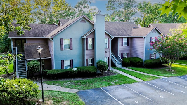 7950 Parklane Ct Unit C, North Charleston, SC 29418 - view of front of house with stairs, uncovered parking, a chimney, a front lawn, and stucco siding