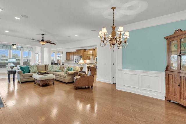 living room featuring ornamental molding, ceiling fan with notable chandelier, and light hardwood / wood-style floors