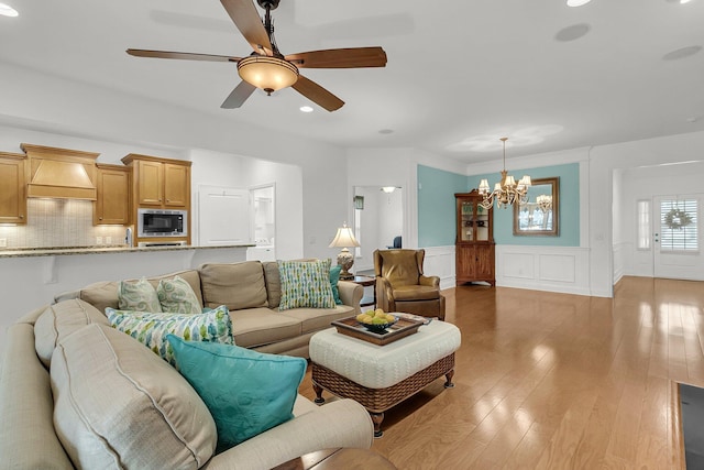 living room featuring ceiling fan with notable chandelier and light hardwood / wood-style floors