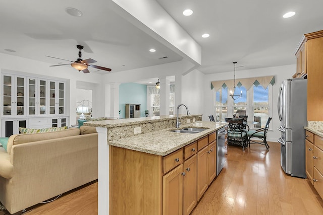 kitchen with sink, light hardwood / wood-style flooring, an island with sink, pendant lighting, and stainless steel appliances