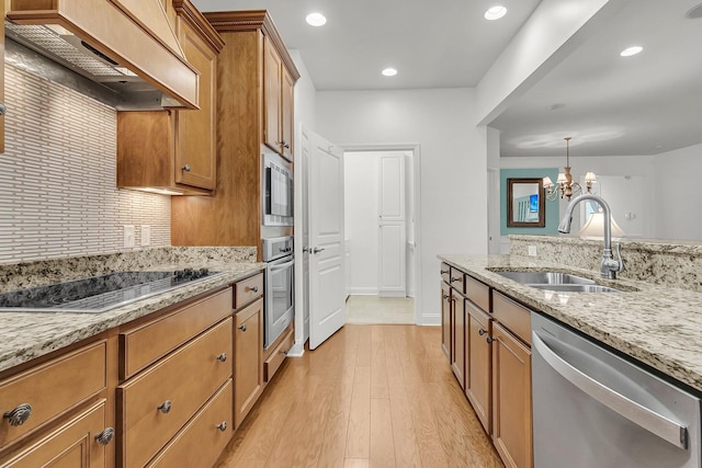 kitchen featuring pendant lighting, sink, appliances with stainless steel finishes, light stone counters, and custom range hood