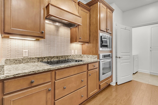 kitchen with stovetop, backsplash, custom range hood, built in microwave, and oven