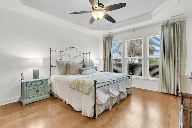 bedroom with crown molding, ceiling fan, a tray ceiling, and light hardwood / wood-style floors