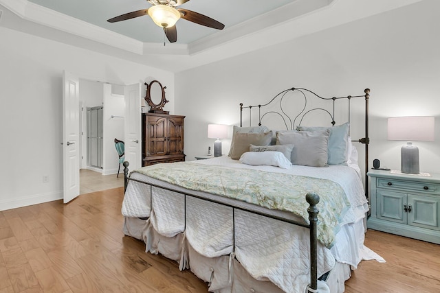 bedroom with a tray ceiling, light hardwood / wood-style flooring, ornamental molding, and ceiling fan