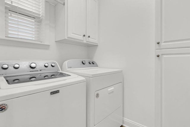 clothes washing area with cabinets and washing machine and clothes dryer