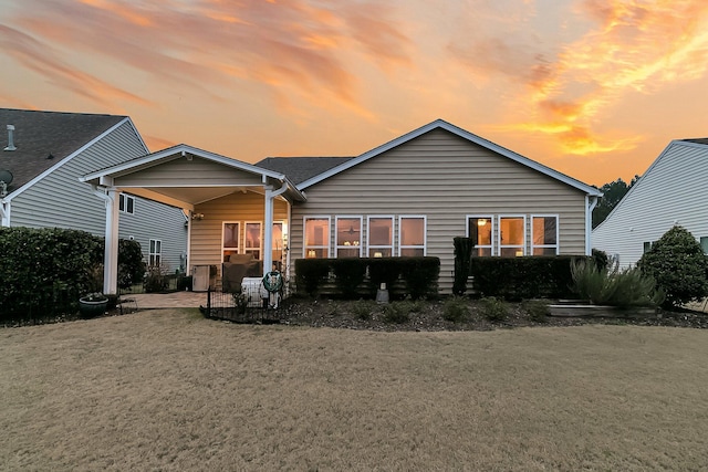 back house at dusk with a yard and a patio