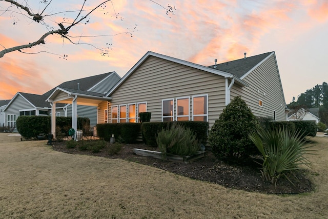 back house at dusk featuring a yard