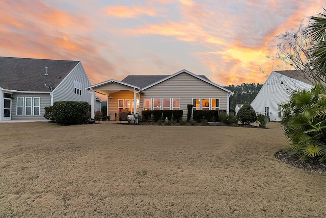 back house at dusk with a lawn