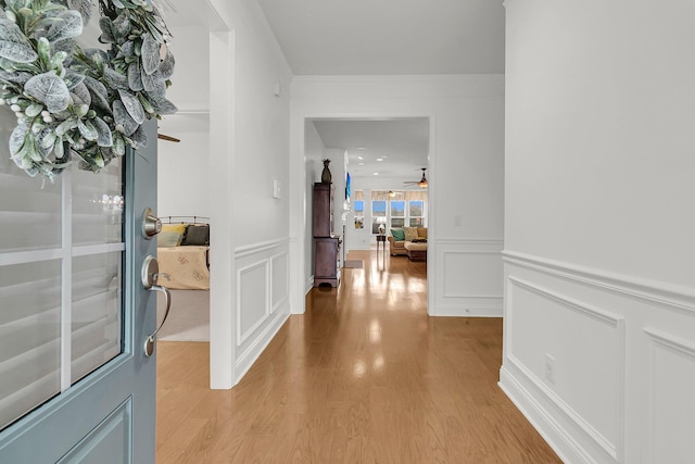 hallway with crown molding and light hardwood / wood-style flooring