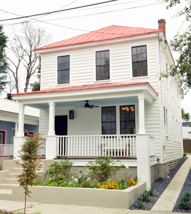 american foursquare style home featuring a porch, metal roof, a standing seam roof, and a chimney