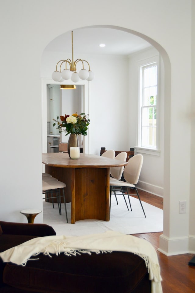 dining room featuring baseboards, wood finished floors, and arched walkways