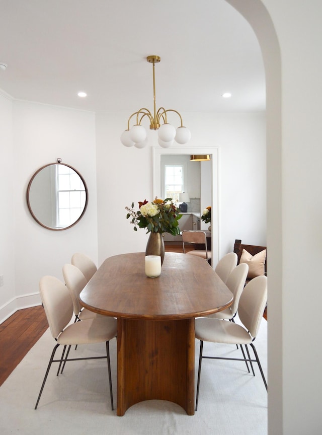 dining room featuring a notable chandelier, light wood finished floors, baseboards, arched walkways, and recessed lighting