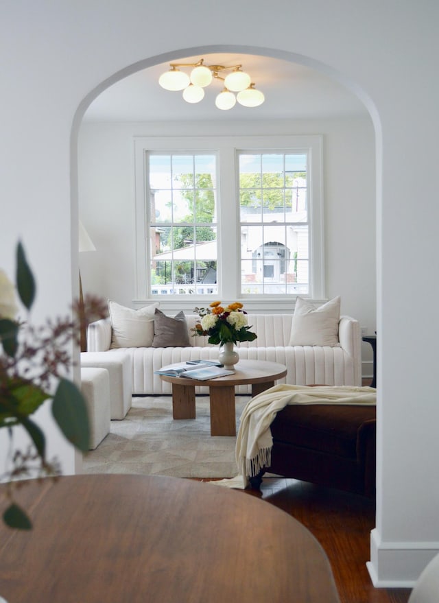 living room with arched walkways, a chandelier, and wood finished floors