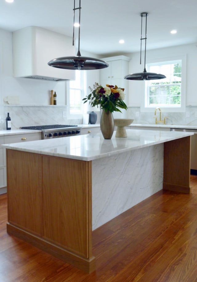 kitchen with dark wood-style floors, stainless steel gas cooktop, white cabinets, and a kitchen island