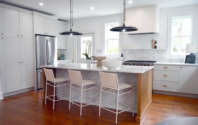 kitchen with freestanding refrigerator, a center island, backsplash, and wood finished floors