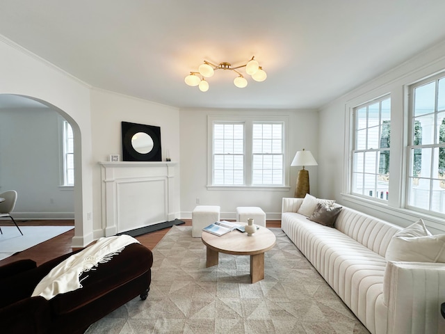 living area with ornamental molding, arched walkways, baseboards, and a chandelier