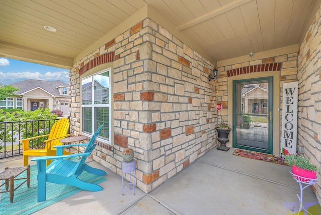 doorway to property featuring stone siding and covered porch