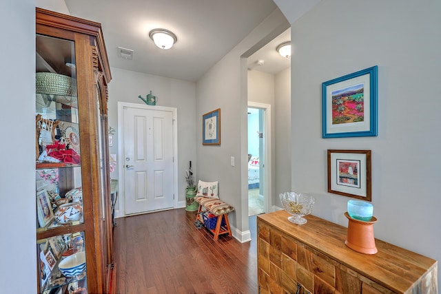 corridor with visible vents, baseboards, and dark wood-style flooring