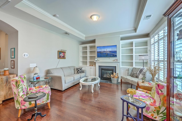living area with visible vents, a fireplace with flush hearth, wood finished floors, and a tray ceiling