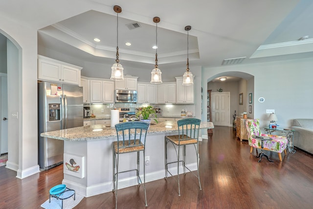 kitchen with arched walkways, a tray ceiling, visible vents, appliances with stainless steel finishes, and dark wood-style floors