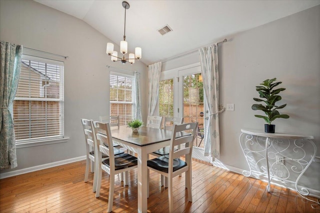 dining room featuring lofted ceiling, hardwood / wood-style flooring, and a chandelier