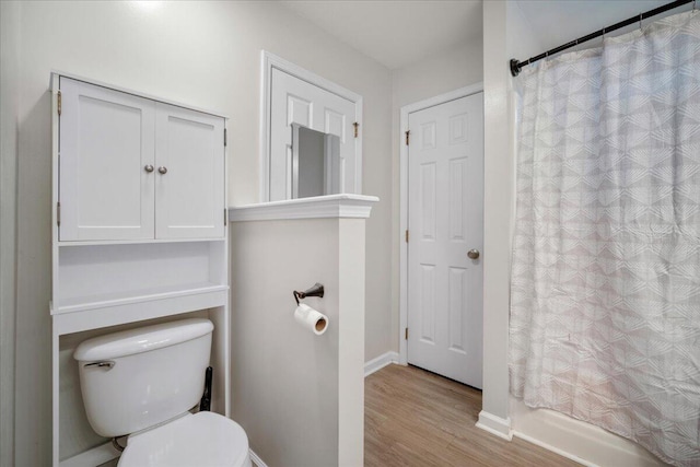 bathroom with hardwood / wood-style floors, a shower with shower curtain, and toilet