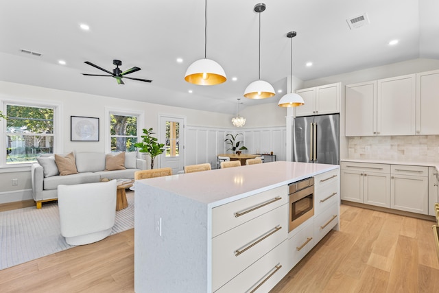 kitchen with pendant lighting, backsplash, white cabinets, light hardwood / wood-style floors, and stainless steel appliances