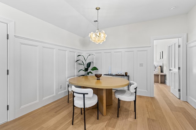 dining space featuring light hardwood / wood-style floors and an inviting chandelier