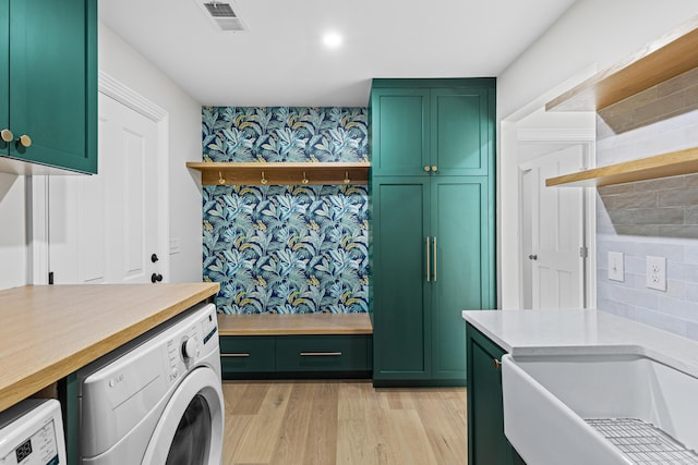 washroom featuring washer and dryer, light hardwood / wood-style floors, cabinets, and sink