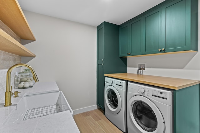 laundry room featuring washer and clothes dryer, cabinets, light wood-type flooring, and sink