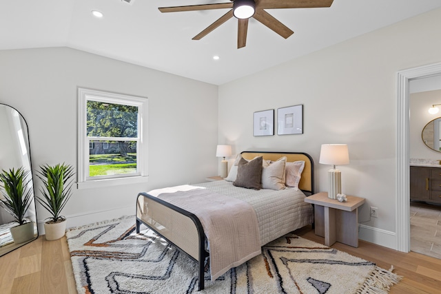 bedroom with ceiling fan, vaulted ceiling, connected bathroom, and light hardwood / wood-style flooring