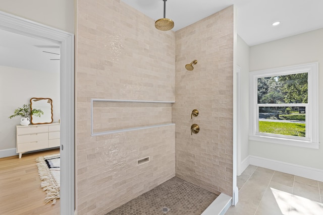 bathroom with a tile shower and wood-type flooring