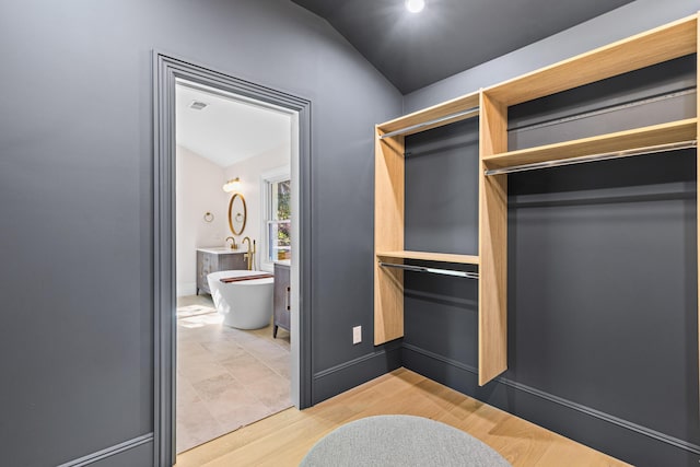 walk in closet featuring hardwood / wood-style flooring and vaulted ceiling