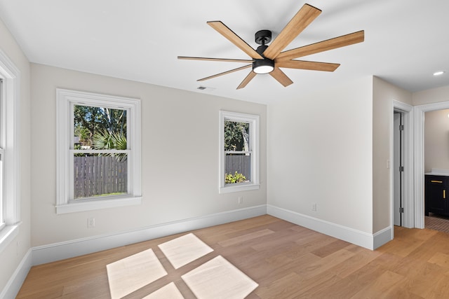 empty room featuring ceiling fan, a healthy amount of sunlight, and light wood-type flooring