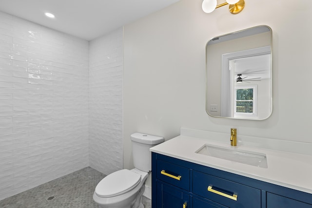 bathroom featuring ceiling fan, toilet, tiled shower, and vanity