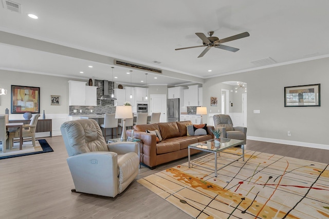 living room with ceiling fan, ornamental molding, and light hardwood / wood-style floors