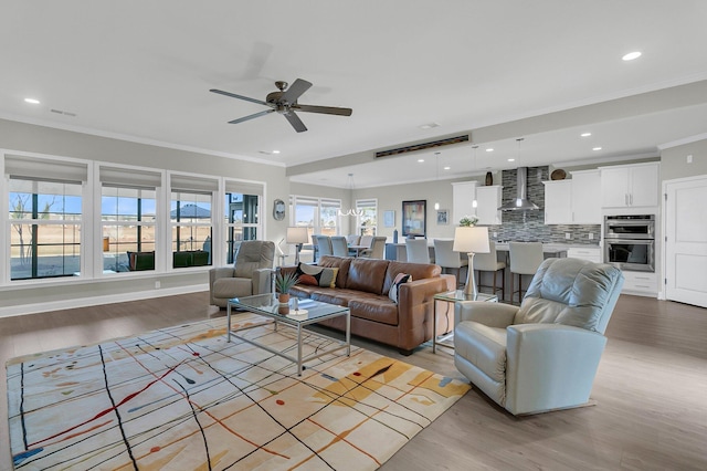 living room with ornamental molding, ceiling fan, and light hardwood / wood-style flooring