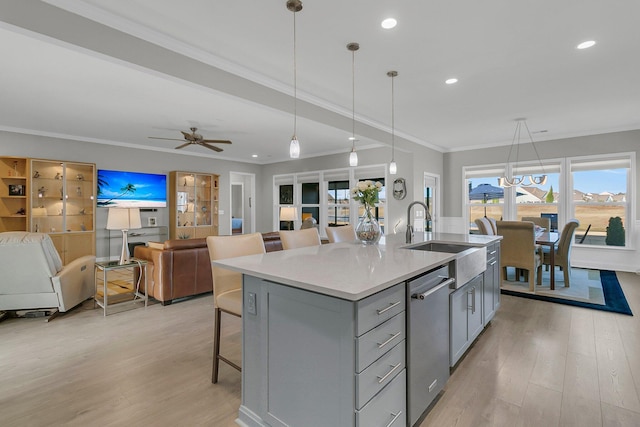 kitchen featuring hanging light fixtures, a breakfast bar area, dishwasher, an island with sink, and sink