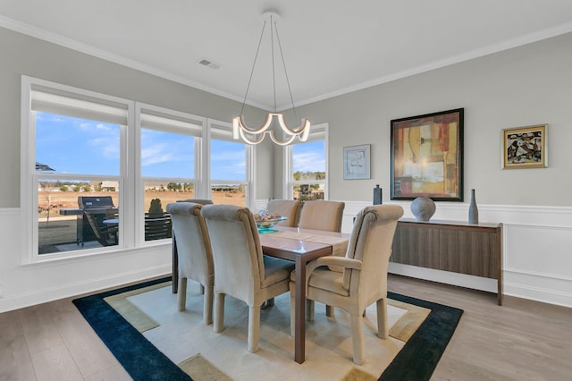 dining space with crown molding, wood-type flooring, and an inviting chandelier