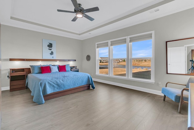 bedroom featuring a tray ceiling, ceiling fan, crown molding, and wood-type flooring