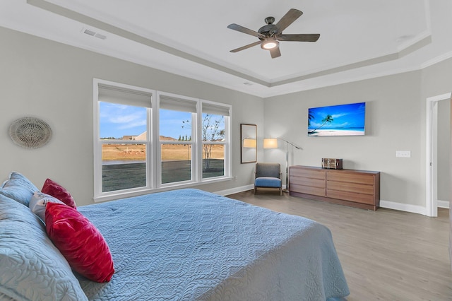 bedroom featuring a tray ceiling, ceiling fan, crown molding, and hardwood / wood-style floors