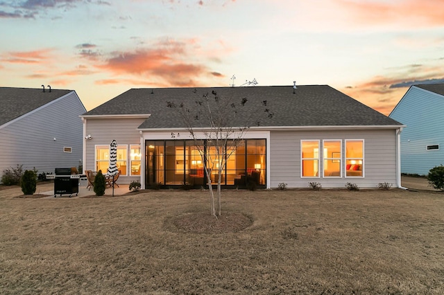 back house at dusk with a patio and a lawn