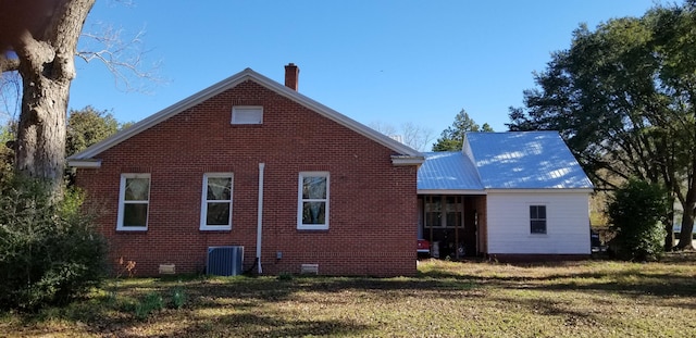 rear view of house featuring central air condition unit and a lawn