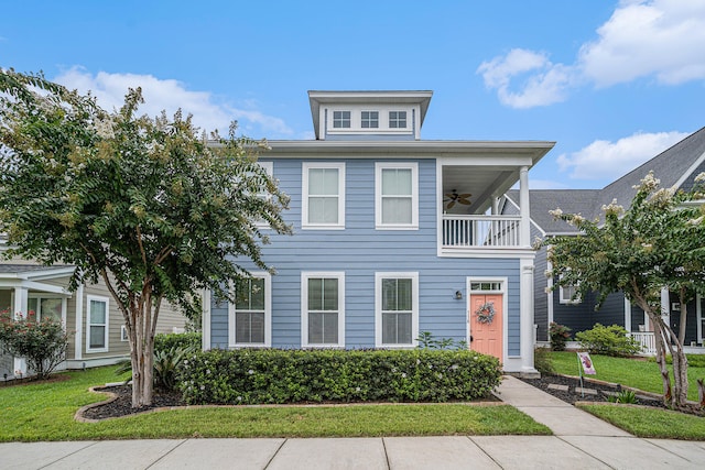 view of front of house featuring a front yard, a balcony, and ceiling fan