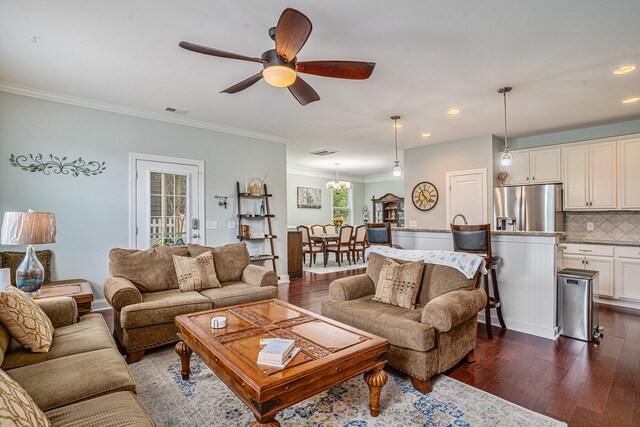 living room featuring ceiling fan with notable chandelier, dark hardwood / wood-style flooring, and crown molding