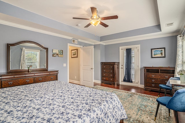 bedroom with dark hardwood / wood-style flooring, a tray ceiling, ceiling fan, and crown molding