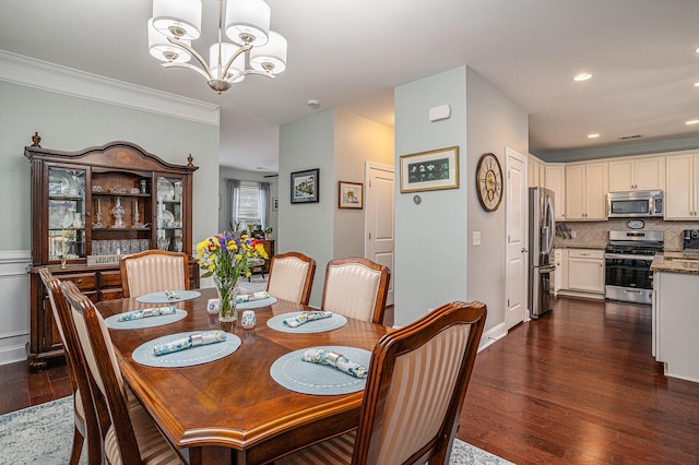 dining space featuring crown molding, dark wood-type flooring, and an inviting chandelier