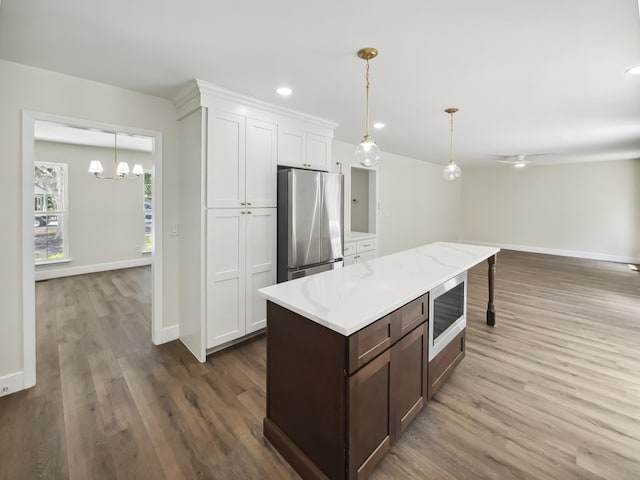 702 Spark St, Mount Pleasant, SC 29464 - kitchen featuring appliances with stainless steel finishes, wood finished floors, white cabinets, decorative light fixtures, and a chandelier