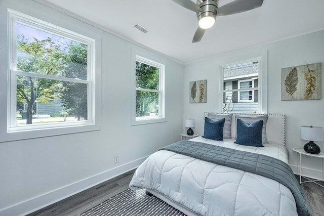 bedroom with dark hardwood / wood-style floors, ceiling fan, and ornamental molding